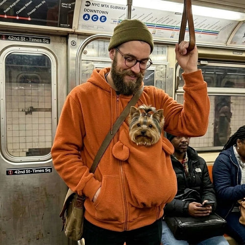Man in an orange Carry-Me Pet Hoodie with a Yorkshire Terrier in the pouch on the subway